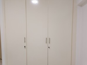Suljettu valkoinen vaatekaappi, jossa on kaksi ovea ja jokaisessa ovi kahva.
