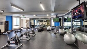 Ein Fitnessraum mit Ergometer, Übungsbällen und einem Fernsehbildschirm.