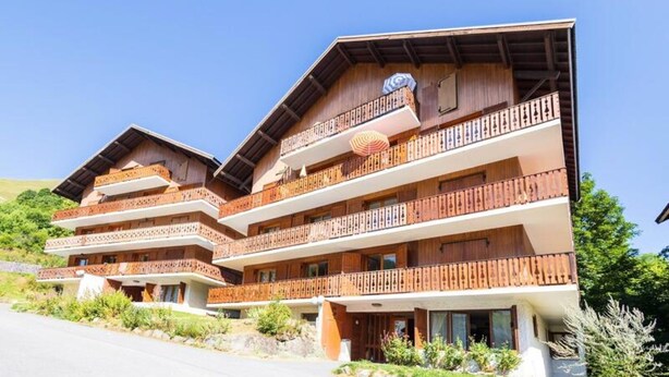 A multi-story wooden chalet with balconies, large windows, and a clear sky. - Apartment in Les Verneys Near Ski Lift (Valloire)
