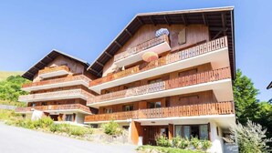A multi-story hotel with wooden balconies and a ski slope visible in the background. - Apartment in Les Verneys Near Ski Lift (Valloire)