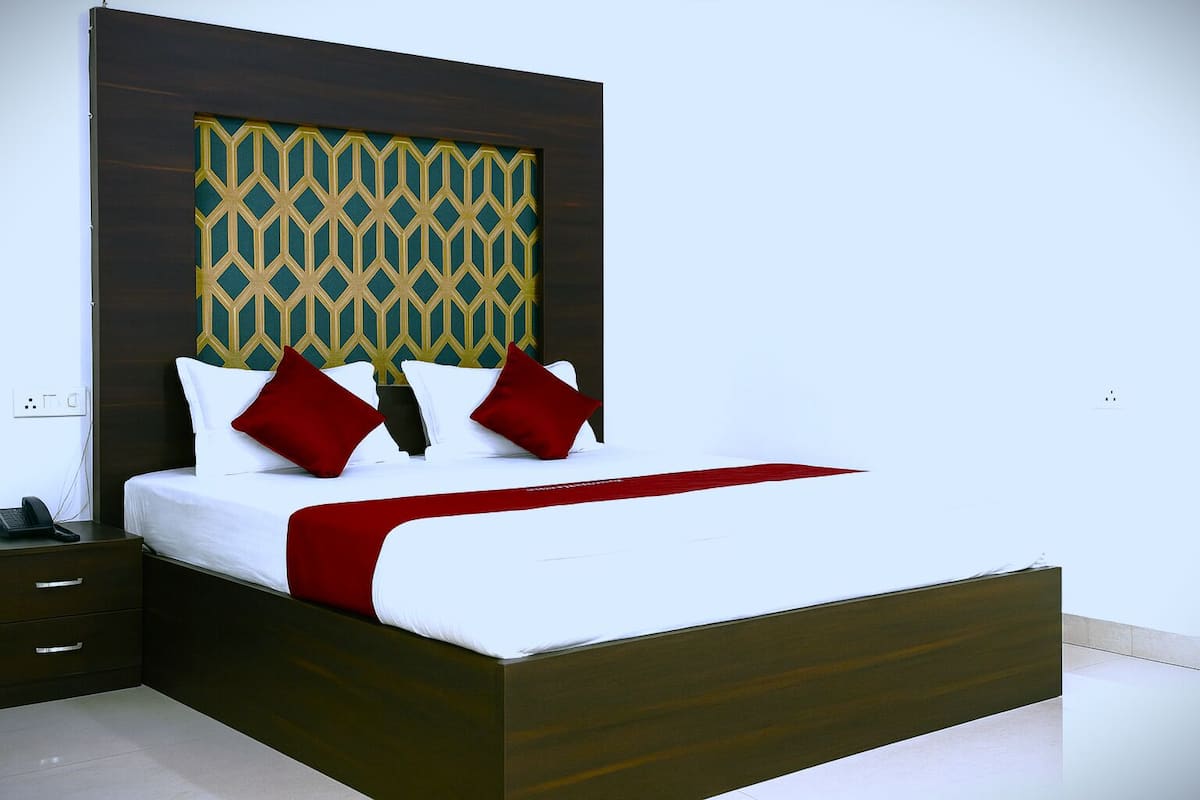 A modern hotel room with a wooden bed frame, white bedding, and a geometric patterned headboard.