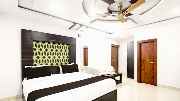 A modern hotel room with a large bed, a ceiling fan, and a patterned headboard. - DARWAR PALACE BY AV HOTEL (Bihar Sharif)