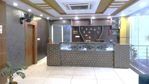 A reception area with a reception desk, a wall-mounted fan, and a ceiling vent. - DARWAR PALACE BY AV HOTEL (Bihar Sharif)