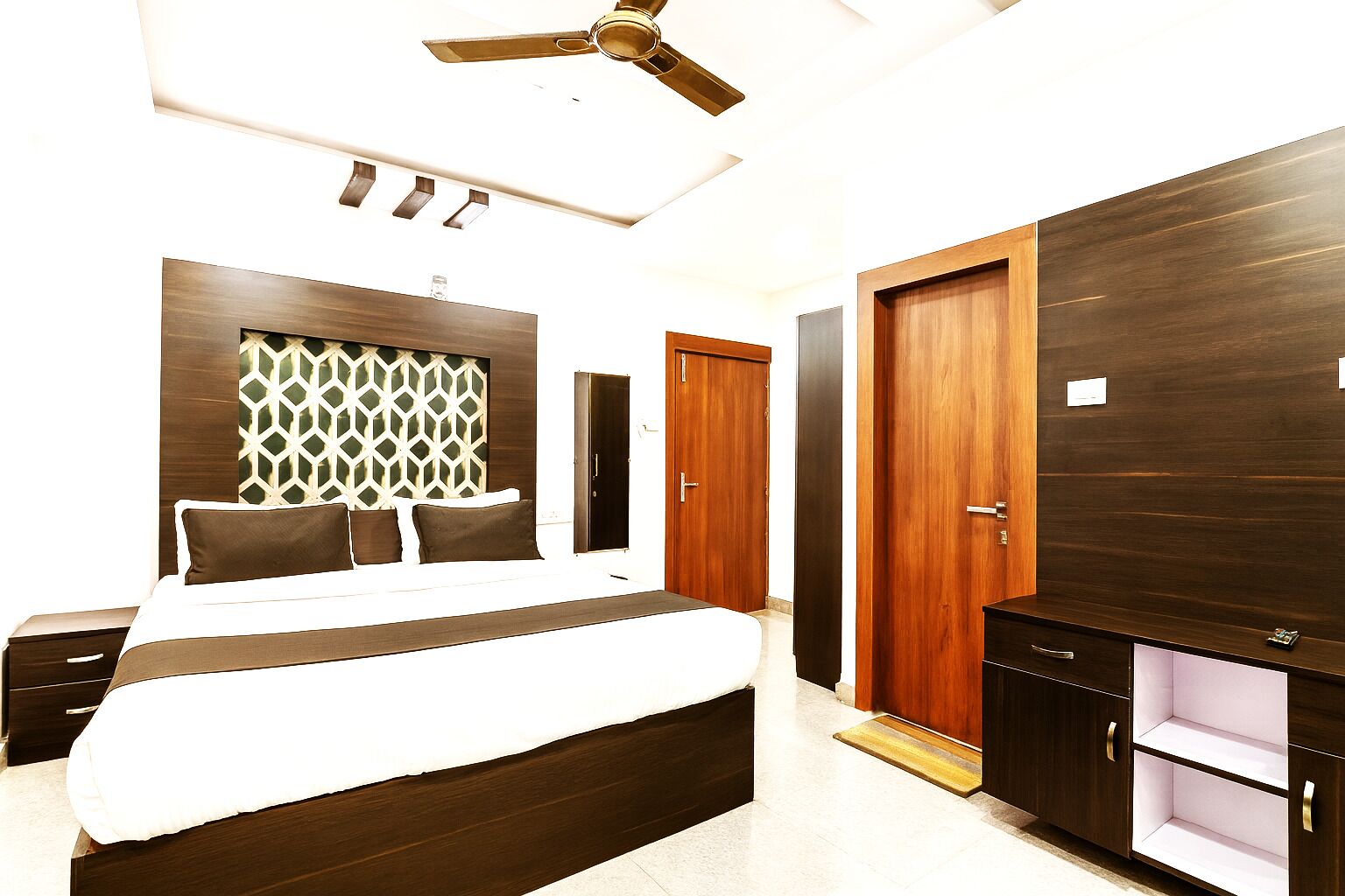 A modern bedroom with a large bed, a wardrobe, and a ceiling fan.