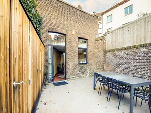 A patio area with a table and chairs, a wooden fence, and a brick wall. - Holiday Home in the Heart of Hasselt (Hasselt)