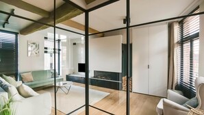 A modern living room with a glass partition, a fireplace, and a sofa. - Holiday Home in the Heart of Hasselt (Hasselt)