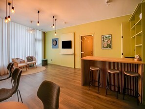 A modern living room with a wooden floor, a bar area with stools, a television, and a dartboard. - Holiday Home in the Heart of Hasselt (Hasselt)