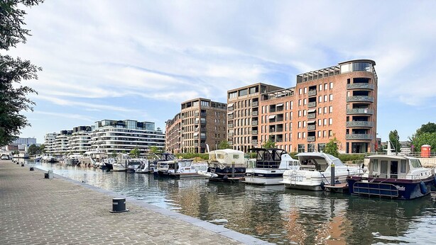 A marina with boats docked alongside a brick building with balconies. - Holiday Home in the Heart of Hasselt (Hasselt)