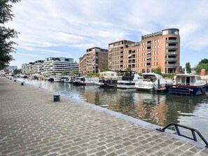 A marina with boats docked alongside a brick building with balconies. - Holiday Home in the Heart of Hasselt (Hasselt)