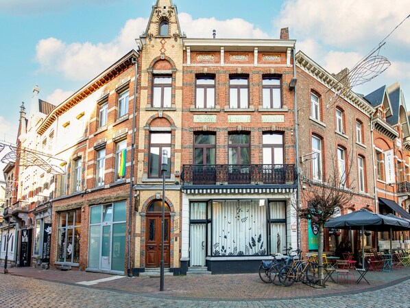 A historic building with a prominent corner entrance, large windows, and a balcony. - Holiday Home in the Heart of Hasselt (Hasselt)