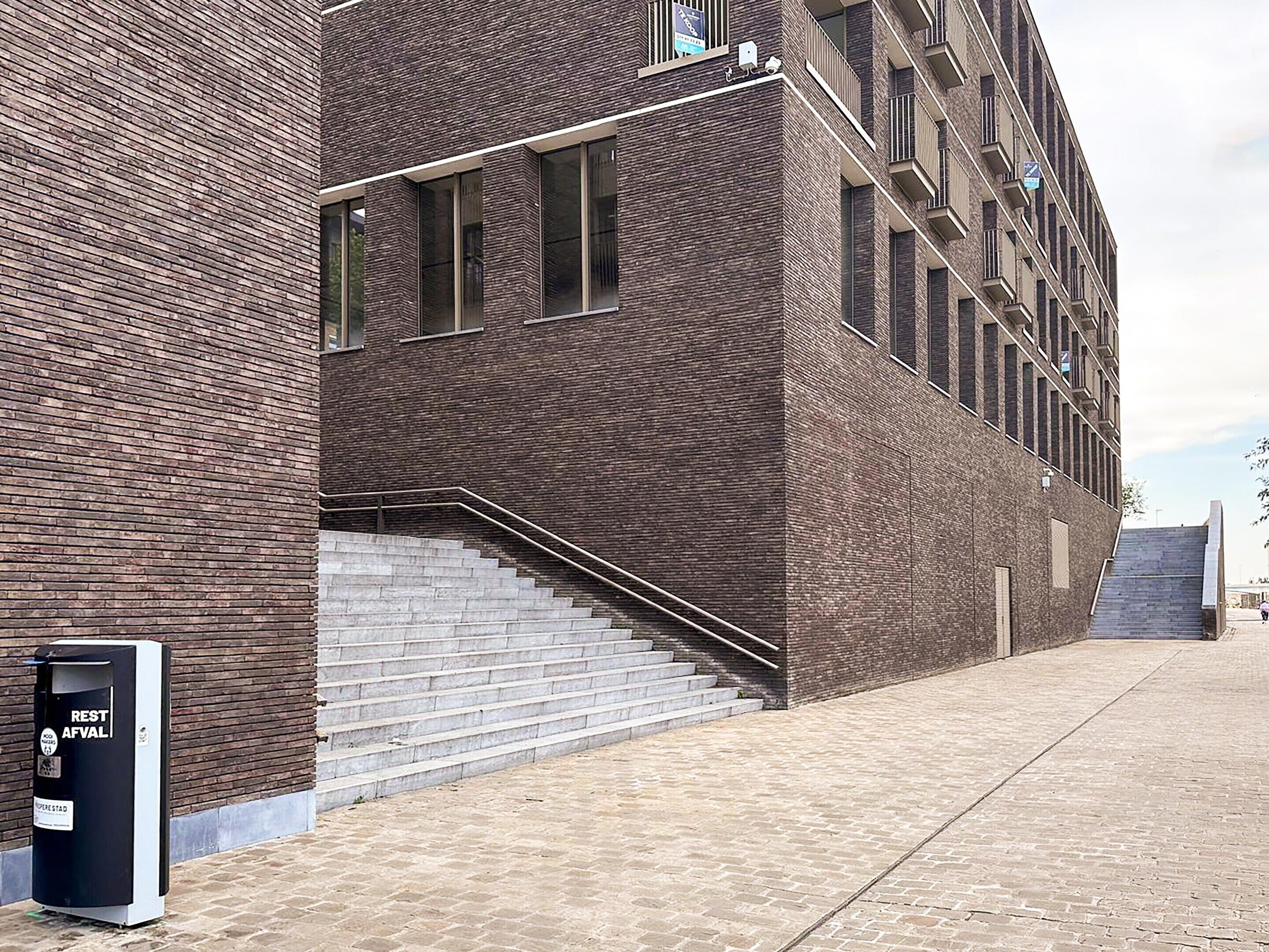 A modern building with a brick facade, a staircase leading to the entrance, and a public restroom sign.