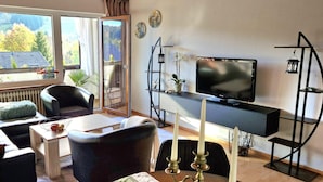 A modern living room with a television, seating, and a view of the outdoors. - House Sunshine on the ski Slope (Herrischried)