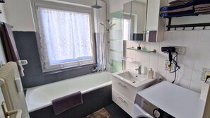 A bathroom with a bathtub, a sink, a mirror, and a window. - House Sunshine on the ski Slope (Herrischried)