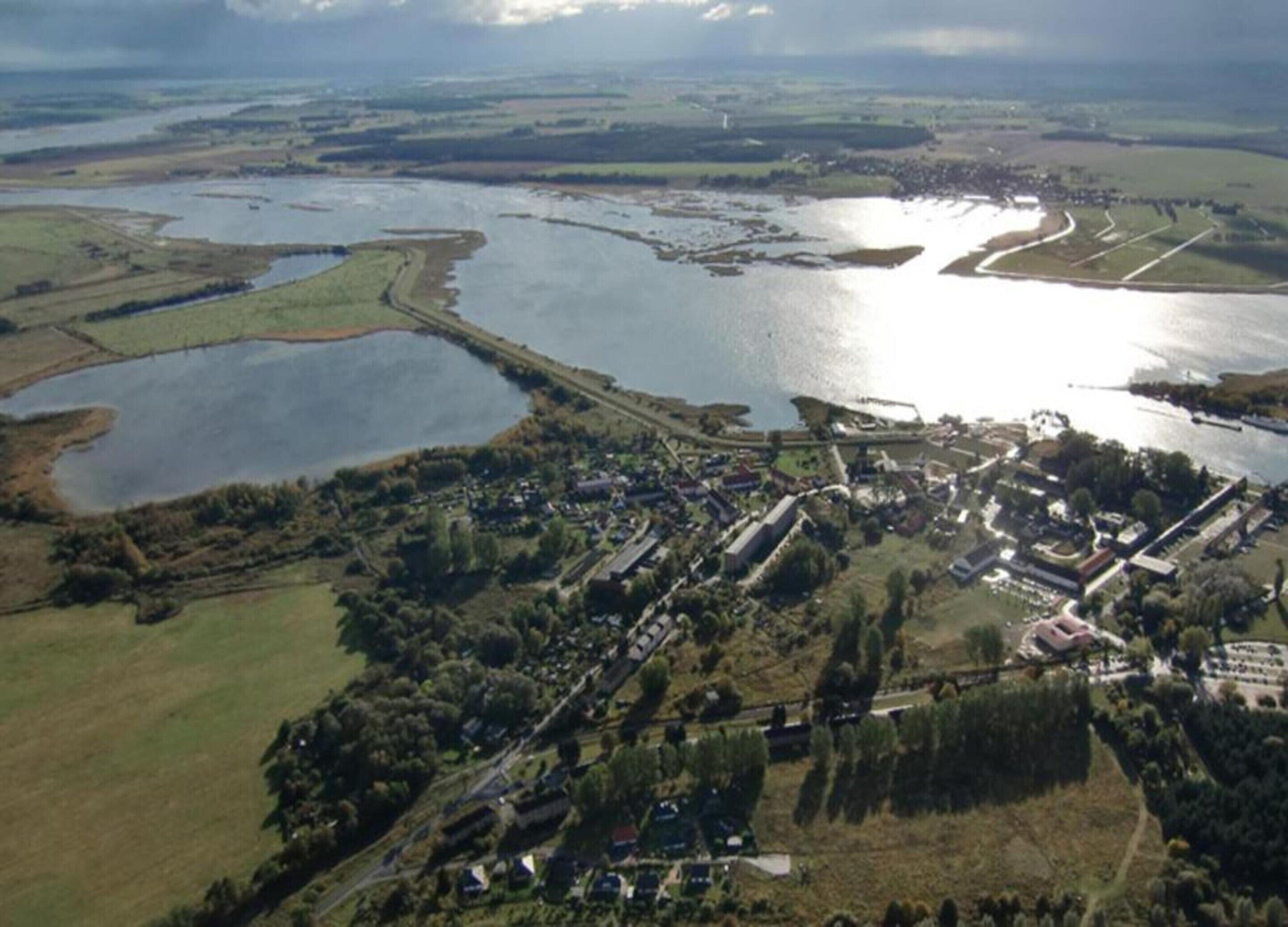 An aerial view of a coastal town with a marina, residential areas, and a large body of water.