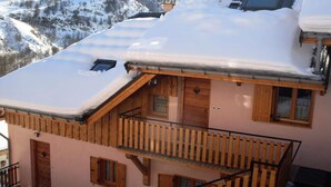A wooden chalet with a balcony and a snow-covered roof, surrounded by mountains. - 3-room Apartment for 6 People, 3-star Rating, South-facing (Valloire)