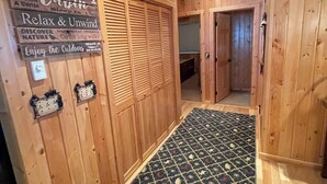 A wooden interior with a patterned rug, wooden walls, and a door leading to another room. - Mountain View Barndominium at Black Bear Ranch (Nordic)