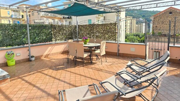 En takterrass med ett avskärmat sittområde, ett bord och stolar.