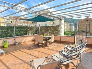 Terraço no telhado com área de estar coberta, uma mesa e cadeiras.