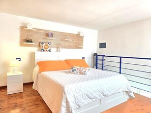 Ein Schlafzimmer mit einem Bett, einem Nachttisch, einem Wandregal und einem Balkongeländer.
