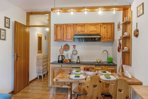 A kitchen with wooden cabinets, a tiled backsplash, and a dining area with a wooden table and chairs.