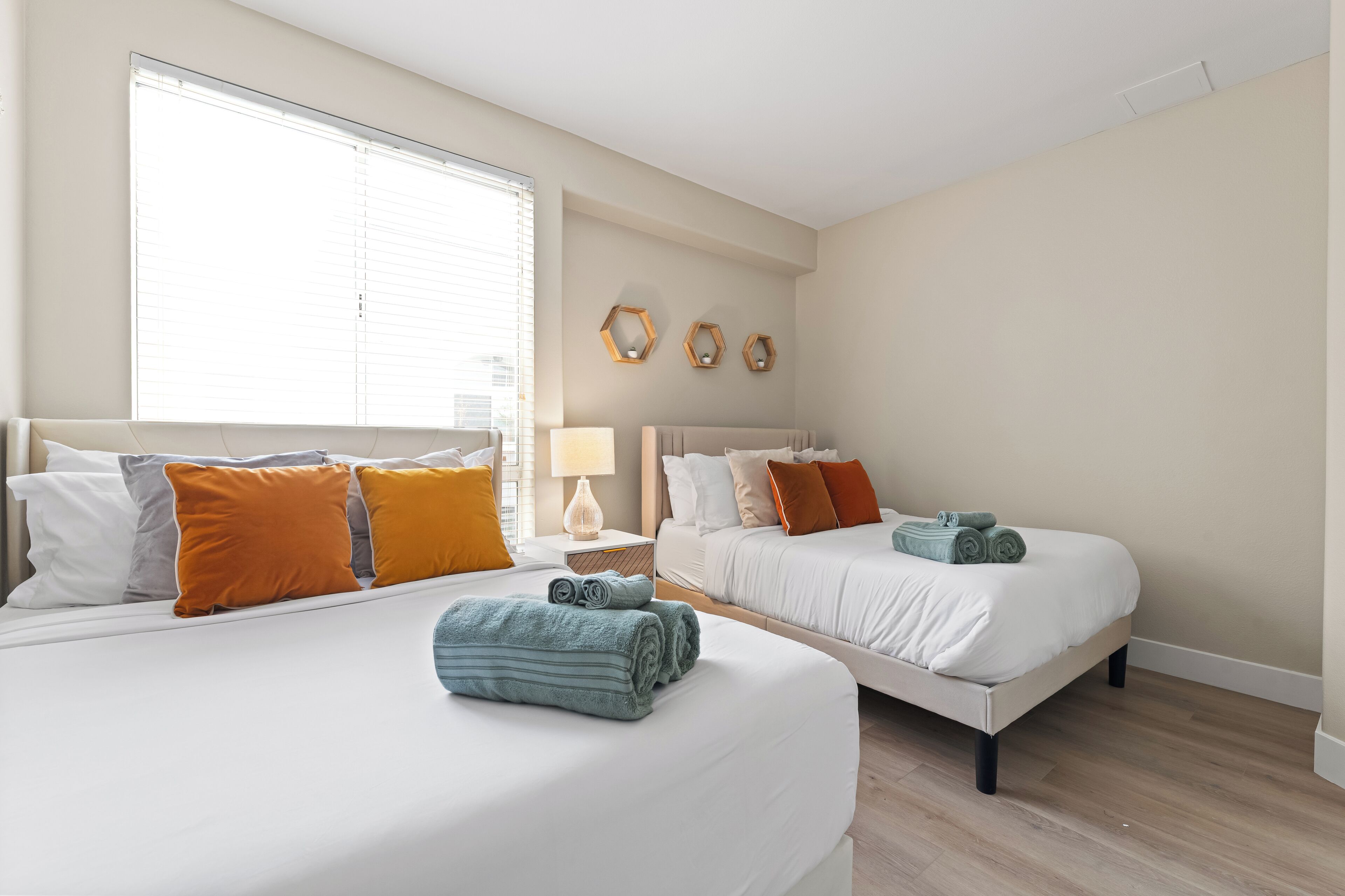 Une chambre d’hôtel avec deux lits, une grande fenêtre et une table de chevet avec une lampe.