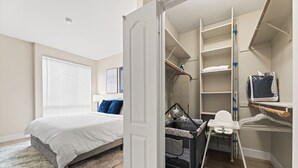 Ein Schlafzimmer mit Bett, Babybett, Schreibtisch und begehbarem Kleiderschrank.