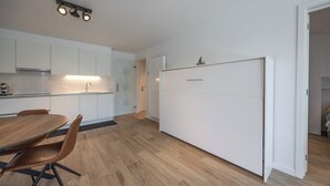 Et moderne køkken med hvide skabe, et træspisebord og et skydelågeskab.
