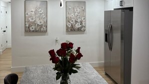 Cozinha moderna com bancada de granito, geladeira de aço inoxidável e duas luminárias pendentes fixadas na parede.