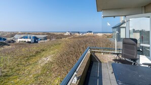 A balcony with a view of the beach and buildings in the distance. - 4-person Apartment With Island-sea View (De Koog)