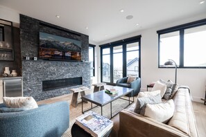 Un salon moderne avec une cheminée en pierre, de grandes fenêtres et des meubles contemporains.