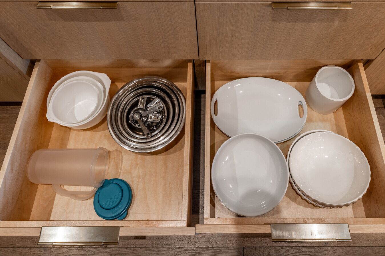 A drawer with various kitchenware including plates, bowls, a teapot, and a kettle.
