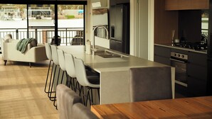 A modern kitchen with a central island, bar stools, and a dining table.