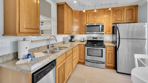 Una cocina moderna con armarios de madera, electrodomésticos de acero inoxidable, encimeras de granito y lavavajillas.