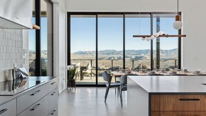 A modern kitchen with a large island, a dining area with a view of the mountains, and a large sliding glass door.