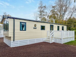 Een stacaravan met een overdekte veranda, een klein terras en een bordje met de tekst 'Salsa'.