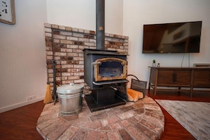 A cozy room with a brick fireplace, a television mounted on the wall, and a wooden cabinet.