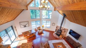 Un salón amplio con techo alto, ventanas grandes, chimenea y televisor.