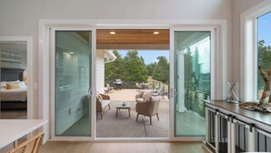 Un interior moderno con un muro de vidrio corredero que da a un patio al aire libre.