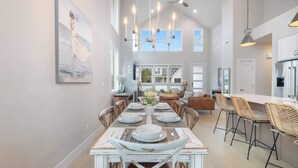 Un comedor amplio con techo alto, iluminación moderna y vistas al exterior.
