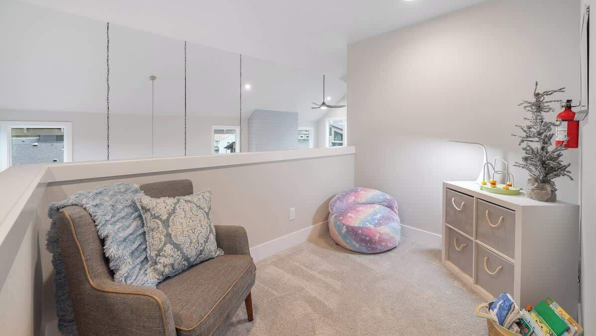 A modern living room with a sofa, a bean bag, a small cabinet, and a bookshelf.