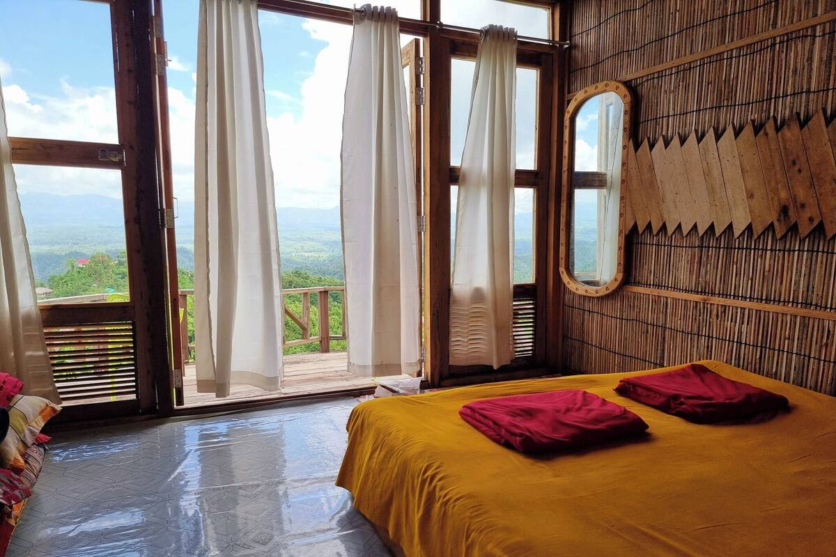 Una habitación con una cama, una ventana con cortinas y vistas al exterior.