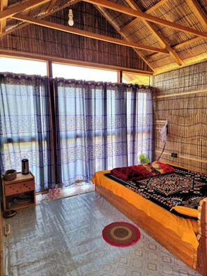 A room with a bed, a small table, and a window with patterned curtains. - Royal Hill Resort Mirinja Valley Lama (Lama)