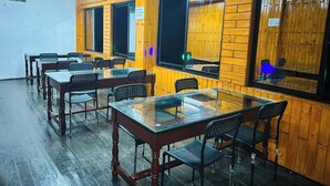 A conference room with wooden paneling, glass tables, and black chairs.
