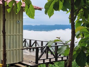 A wooden deck with a metal railing, overlooking a mountainous landscape with clouds below. - Royal Hill Resort Mirinja Valley Lama (Lama)