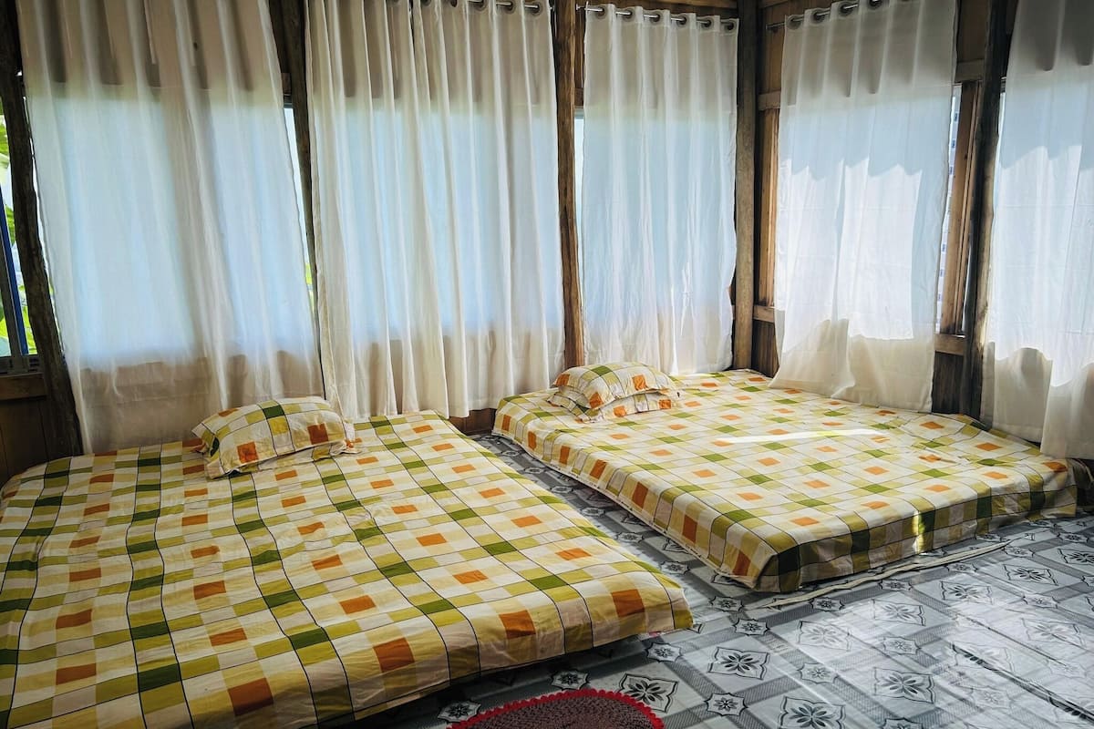 Una habitación con dos camas, cada una con un edredón a cuadros y un piso estampado.