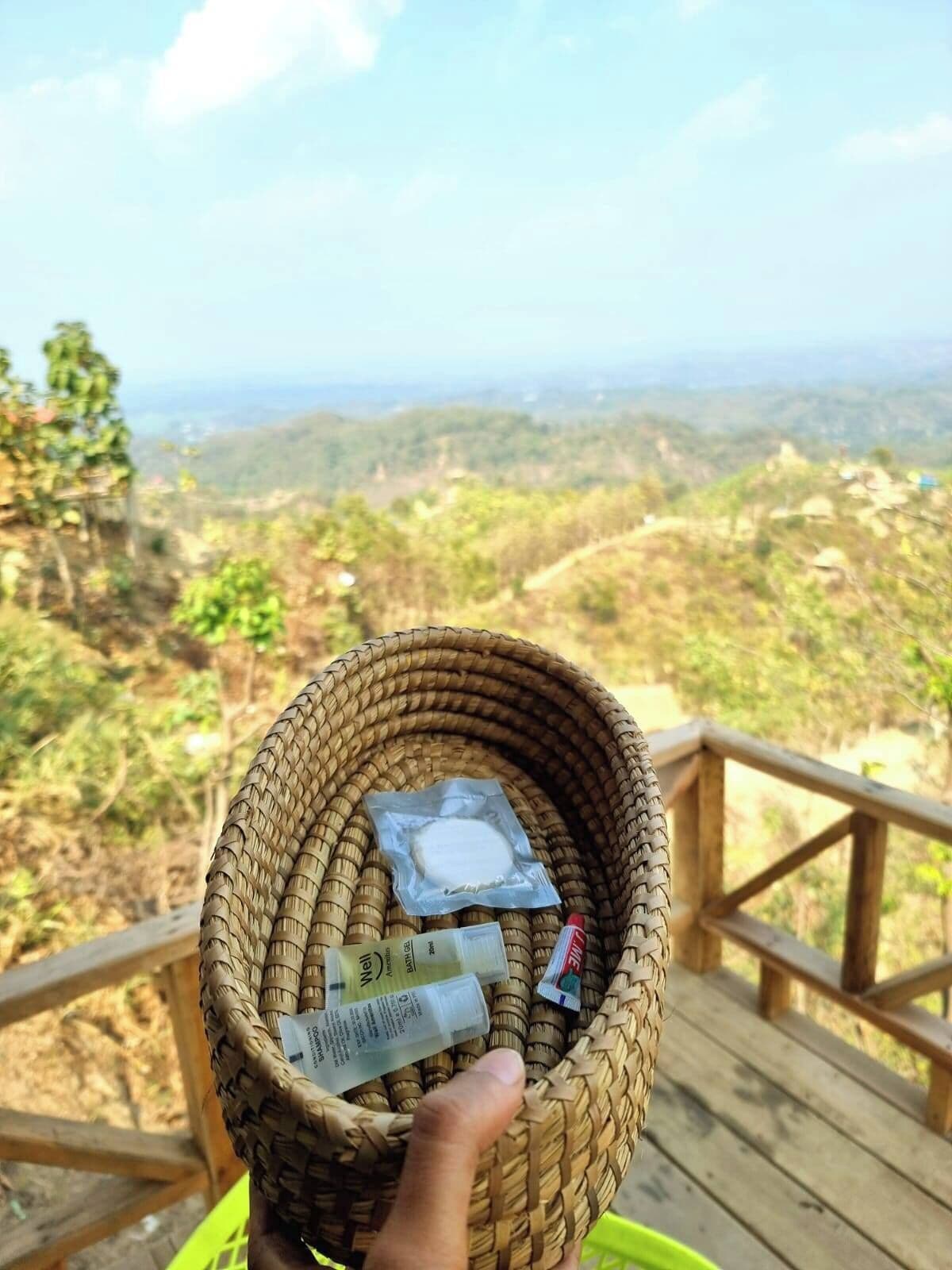 A wicker basket on a wooden deck with a scenic view of a hilly landscape in the background.