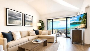 Una sala moderna con un sofá seccional color beige, una mesa de centro y un televisor sobre un mueble de madera.