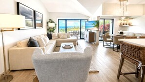 Una sala de estar moderna con sofá, sillón y comedor.