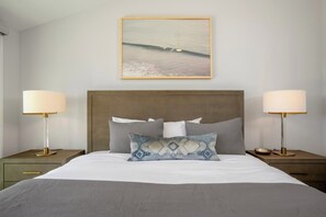 A neatly made bed with a headboard, two bedside lamps, a framed picture above the bed, and a nightstand with a drawer. - Kapalua Golf | Golf View 6 BR, Sleeps 18 | Car Incl. w/ 6+ Nights | KGV ML-2327 by KBM (Lahaina)