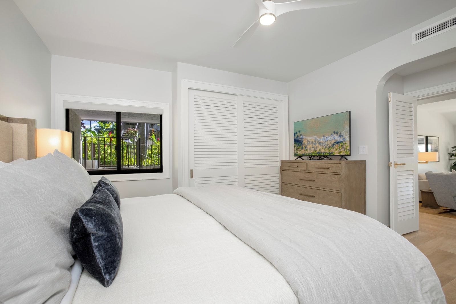 Ein Schlafzimmer mit Bett, Fenster mit Aussicht, einem Schminktisch und einem Bild an der Wand.